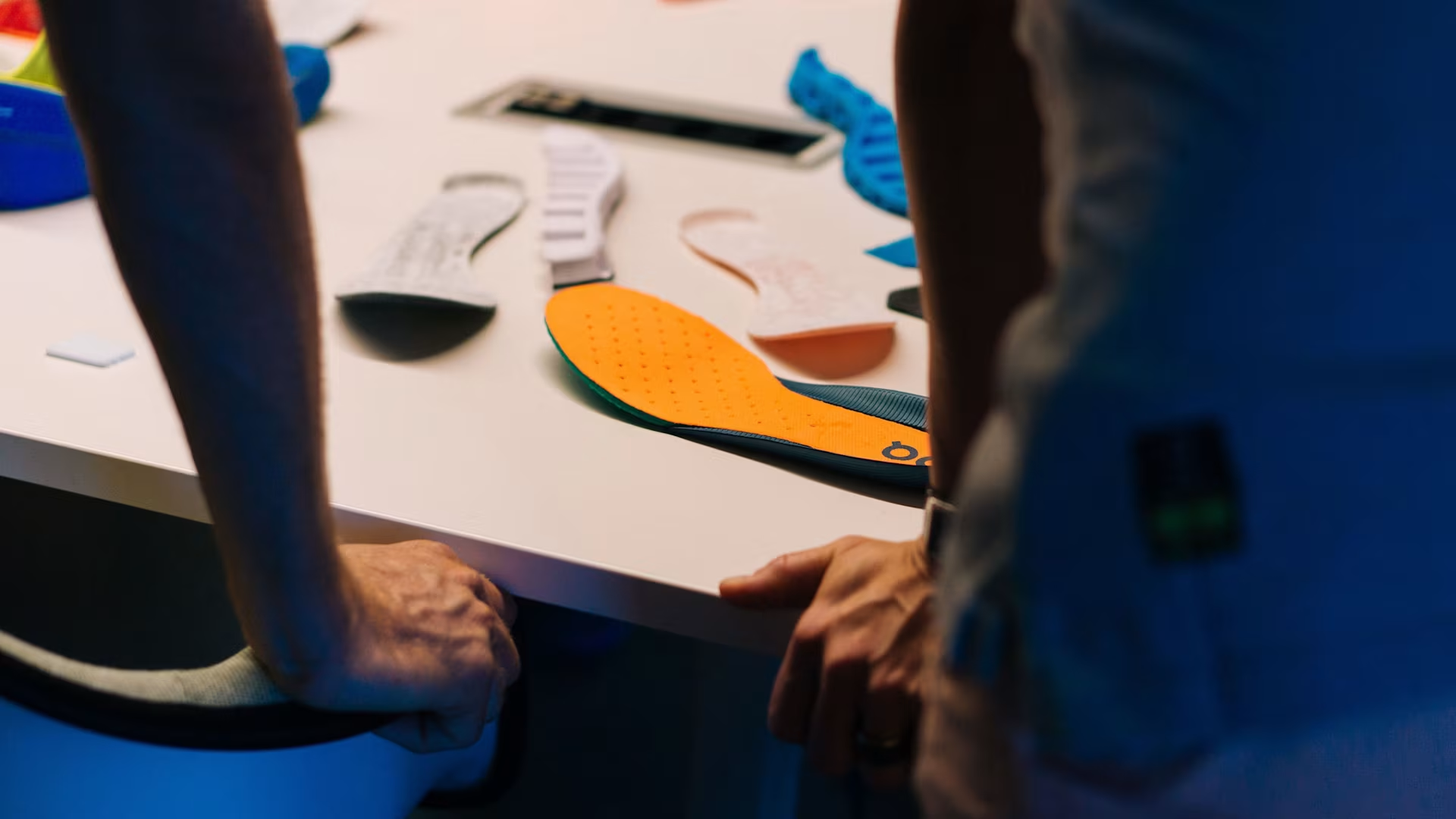 Two people stand at a desk, with colorful Speedboards scattered around it.